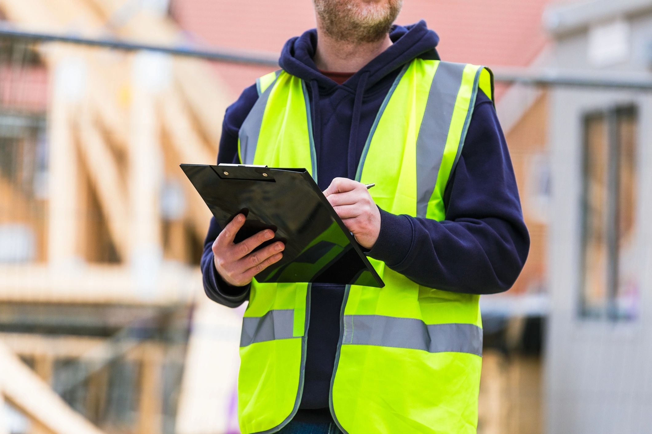 Construction worker reviewing documents on a clipboard at a construction site